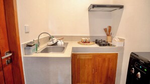 A compact kitchen with a sink, wooden cabinets, a gas stove, and a built-in range hood. - Bali Bay By Urban Haven (Denpasar)