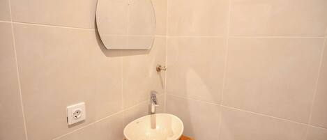 A bathroom with a round mirror, a sink, and a wooden vanity.