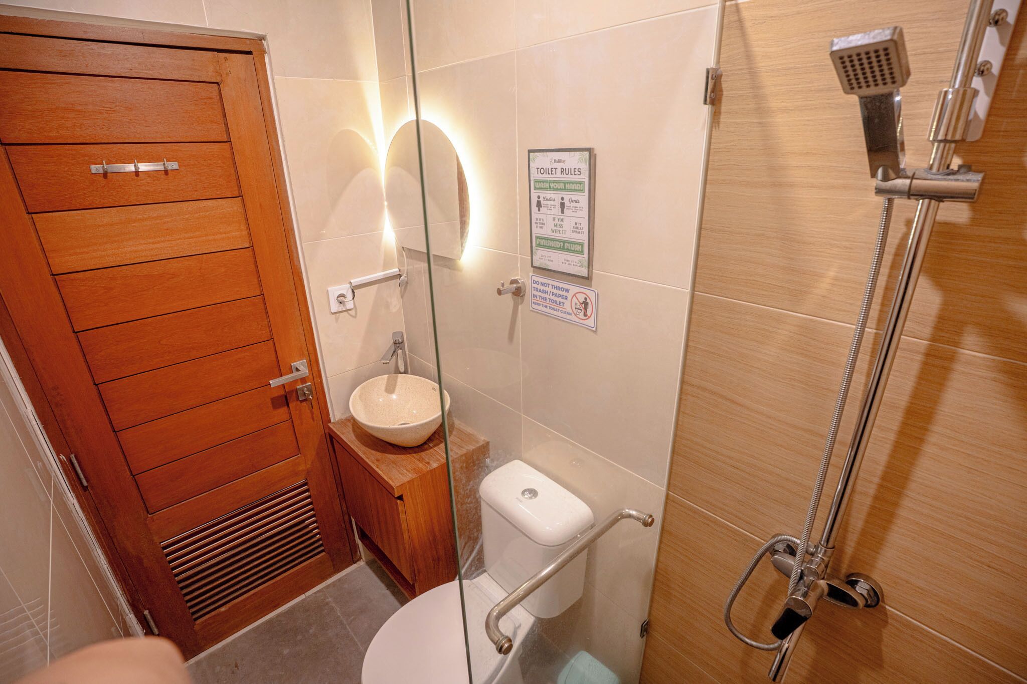 A bathroom with a wooden door, a sink, a toilet, and a shower.