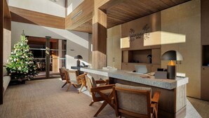 A modern lobby with a central island, wooden chairs, a Christmas tree, and a reception desk.