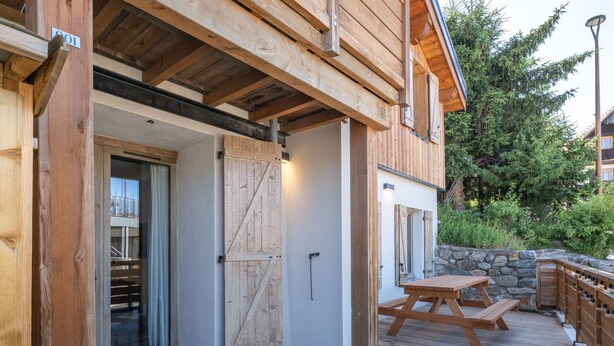 Una terraza de madera con una mesa de picnic y un muro de piedra.