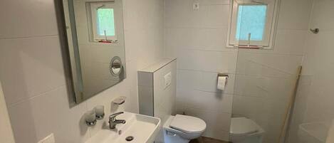 Ein modernes Badezimmer mit Waschbecken, Toilette und Duschbereich.