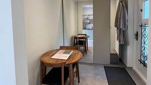 Un interior moderno con una mesa de comedor, sillas, un espejo y vistas hacia una zona de cocina.