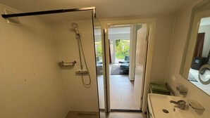 Un baño con ducha, lavamanos y puerta de vidrio que da a un patio.