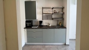 Una cocina moderna con gabinetes grises, un microondas, una cafetera y un estante con frascos de vidrio.