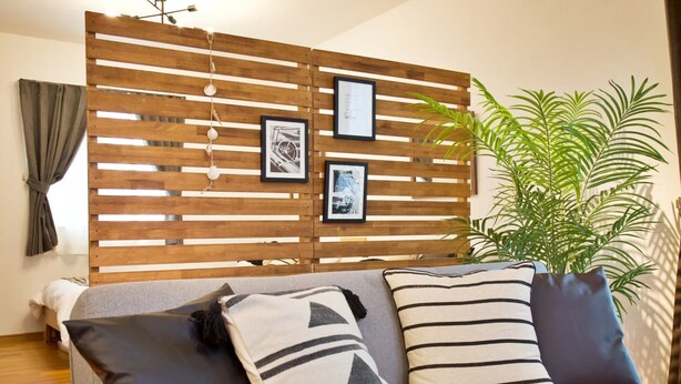 Una sala de estar moderna con un tabique de madera, un sofá con cojines a rayas y una planta en maceta.