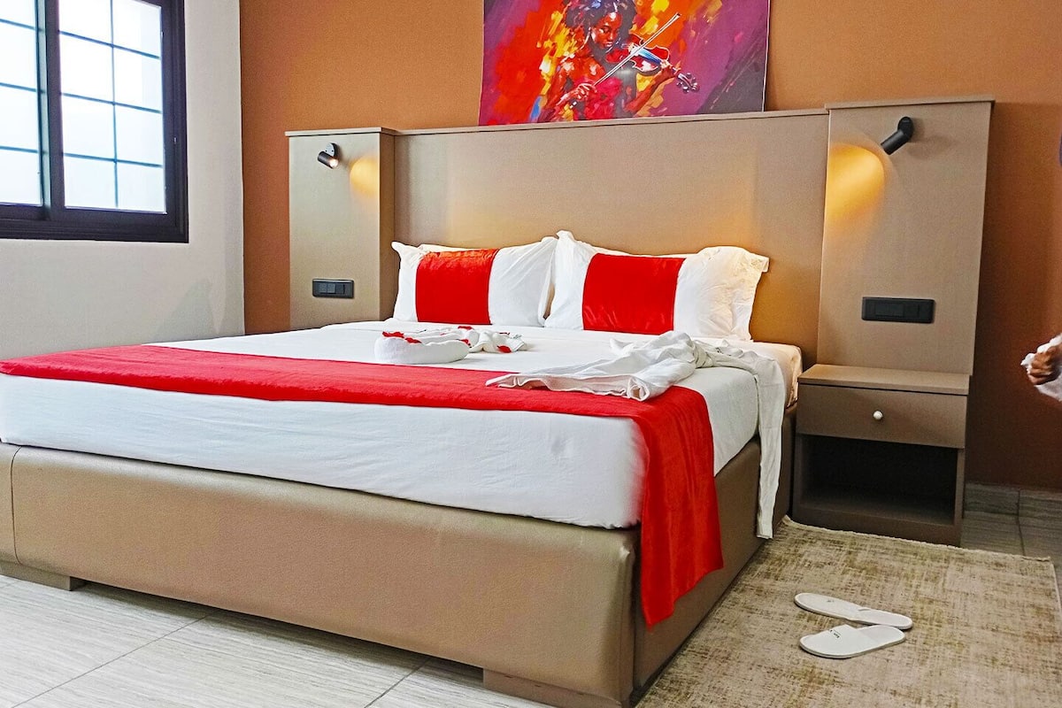 Ein Hotelzimmer mit einem großen Bett, einem Nachttisch, einer Nachttischlampe und einem Gemälde an der Wand.