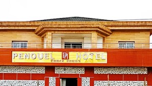 Un hotel llamado "Penuel Hotel" con un letrero amarillo que muestra números de contacto.