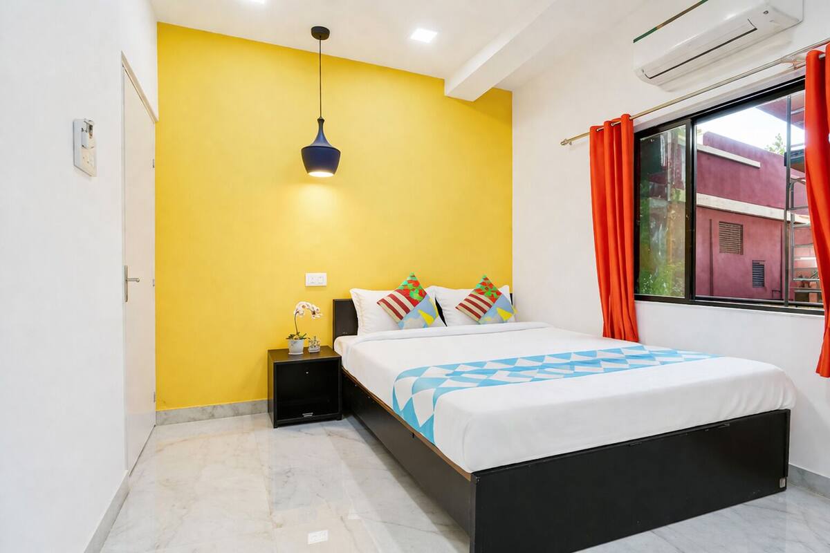 A bedroom with a bed, nightstand, and a hanging light fixture.