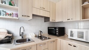 A kitchen with wooden cabinets, a stainless steel sink, a kettle, a toaster oven, and a microwave.