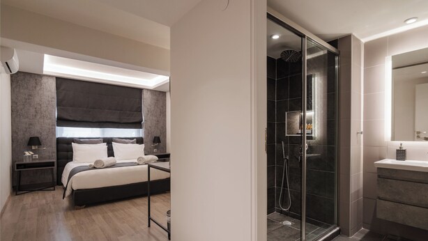A modern bedroom with a large bed, bedside tables, and a glass-enclosed shower area.