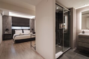 A modern bedroom with a large bed, bedside tables, and a glass-enclosed shower area. - Acropolis Boutique Residence, Bill & John Apartments & Villas (Athens)