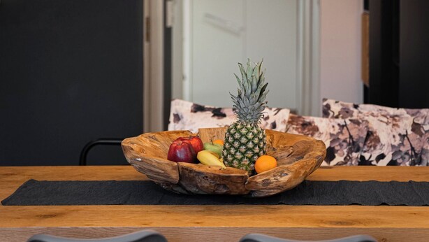 A dining area with a wooden table, a bowl of fruit, and pendant lights. - Acropolis Grand Residence | Syggroy Av.12, Athens 11742, Bill & John Apartments & Villas (Athens)