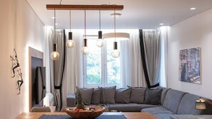 A modern living room with a wooden dining table, grey sofa, and a wooden ceiling. - Acropolis Grand Residence | Syggroy Av.12, Athens 11742, Bill & John Apartments & Villas (Athens)