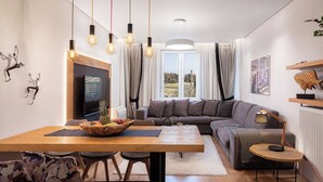 A modern living room with a wooden dining table, a sofa, and a TV. - Acropolis Grand Residence | Syggroy Av.12, Athens 11742, Bill & John Apartments & Villas (Athens)