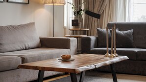 Ett modernt vardagsrum med ett soffbord i trä, två grå soffor, en golvlampa och ett litet sidobord med en växt.