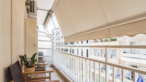Un balcon avec un espace salon, un pot de fleurs et une vue sur le paysage urbain.