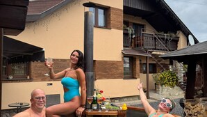 A hot tub with three people, surrounded by flowers and a house with a balcony. - Privát Prima (Podturen)