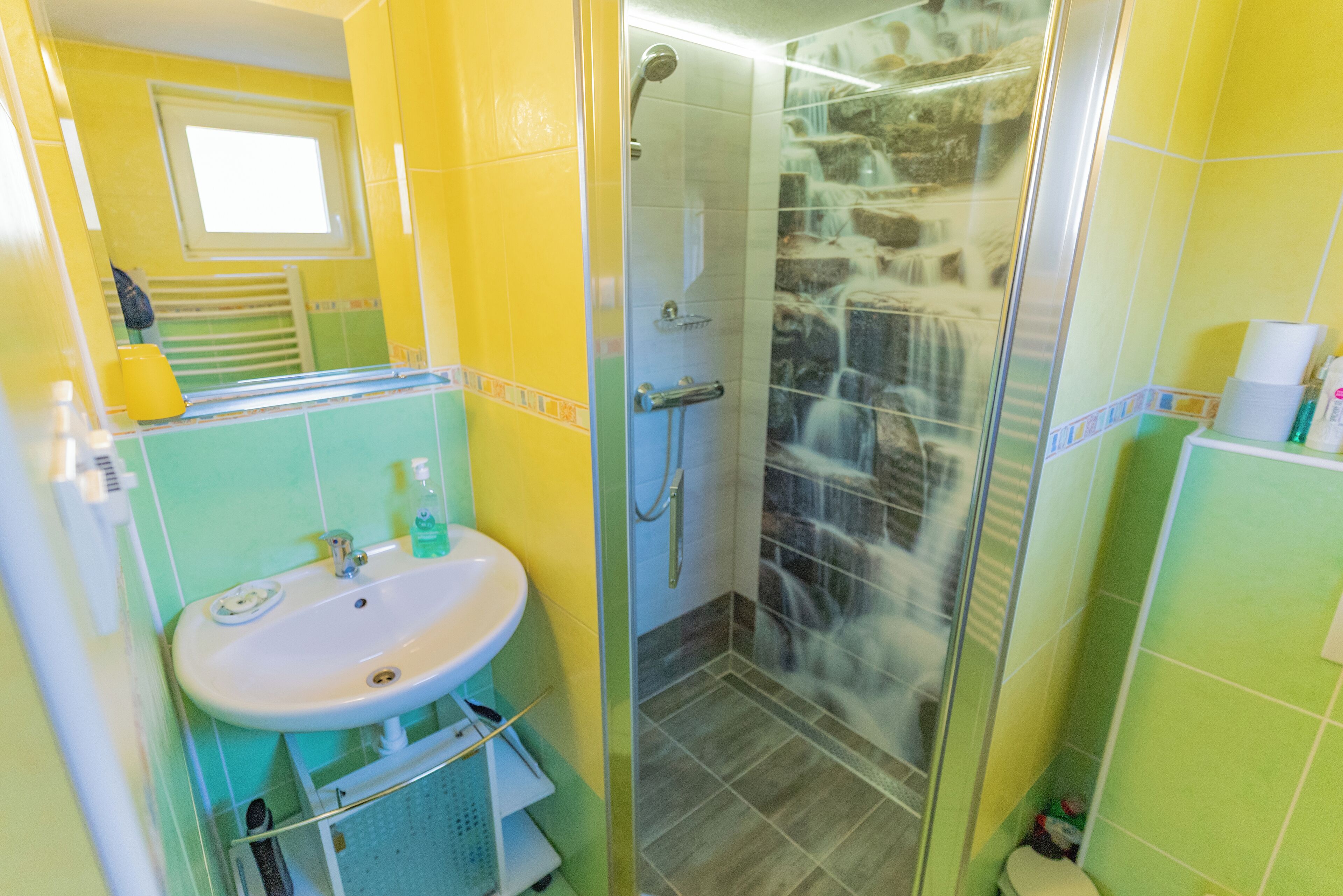 Un baño con lavamanos, espejo y ducha.