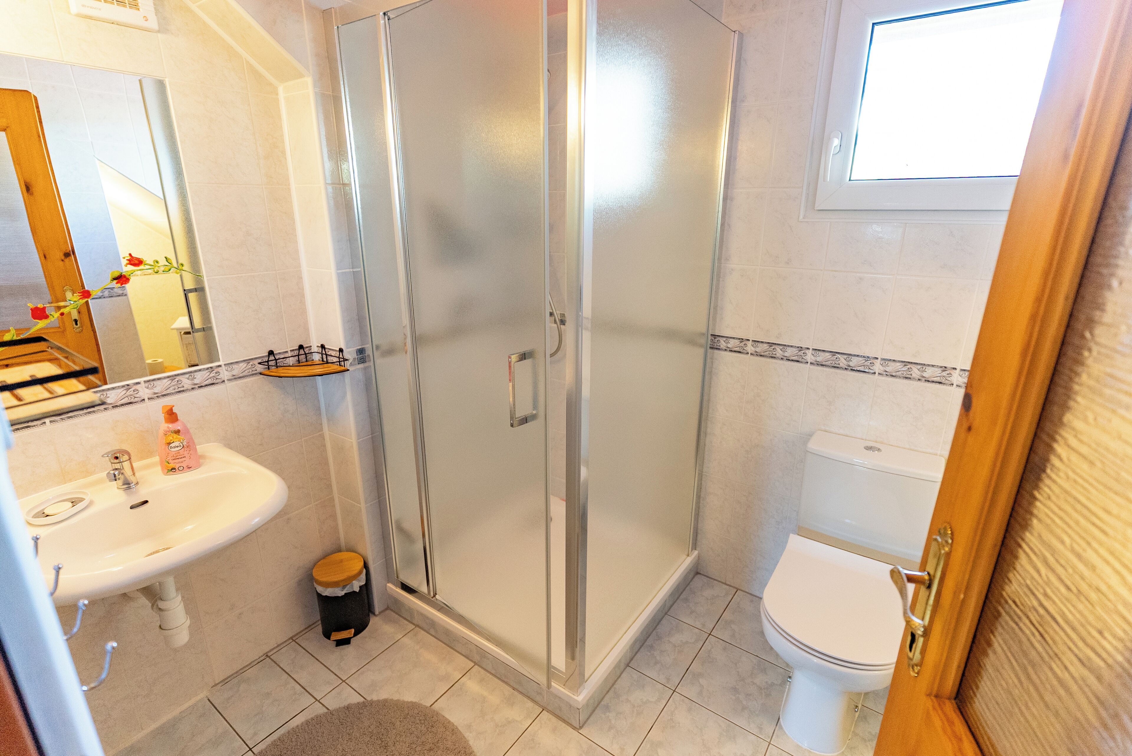 Ein Badezimmer mit Duschkabine, Waschbecken mit Spiegel und Toilette.