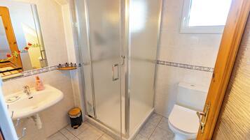Une salle de bain avec une douche à parois de verre, un lavabo avec un miroir et des toilettes.