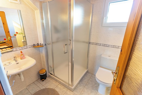 A bathroom with a glass-enclosed shower, a sink with a mirror, and a toilet. - Privát Prima (Podturen)