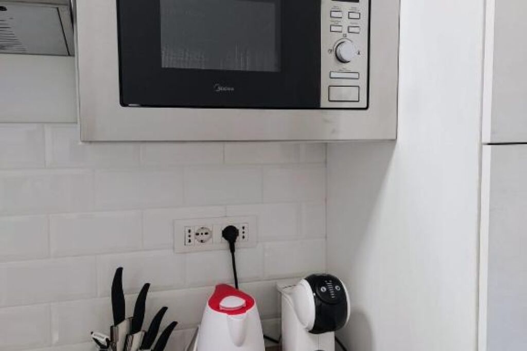 A kitchen with a microwave, a kettle, and a coffee maker.