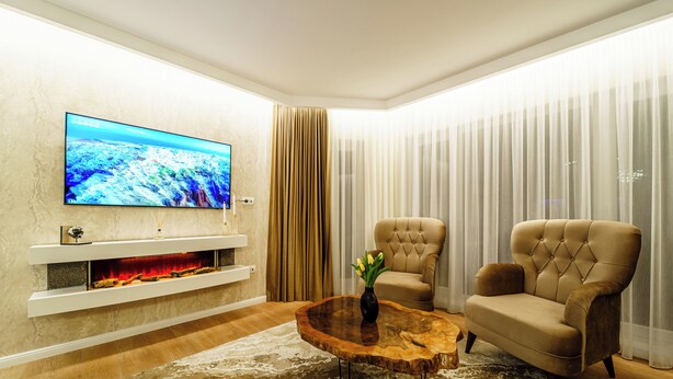Uma sala de estar moderna com televisão de tela plana, lareira, mesa de centro redonda e duas poltronas.