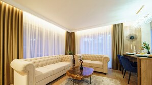 Uma sala de estar moderna com dois sofás bege, uma mesa de centro de madeira e um espaço de jantar com uma mesa e cadeiras de madeira.
