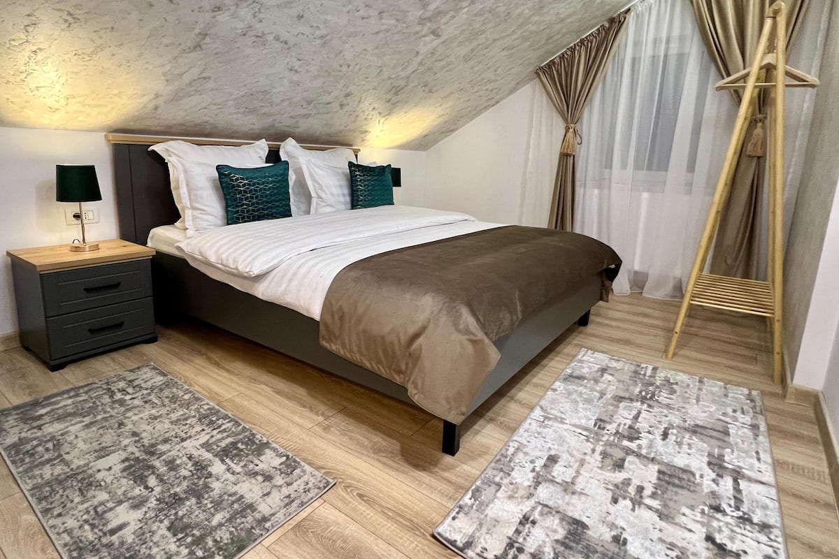 Een slaapkamer met een bed, nachtkastjes, een lamp en een houten vloer.
