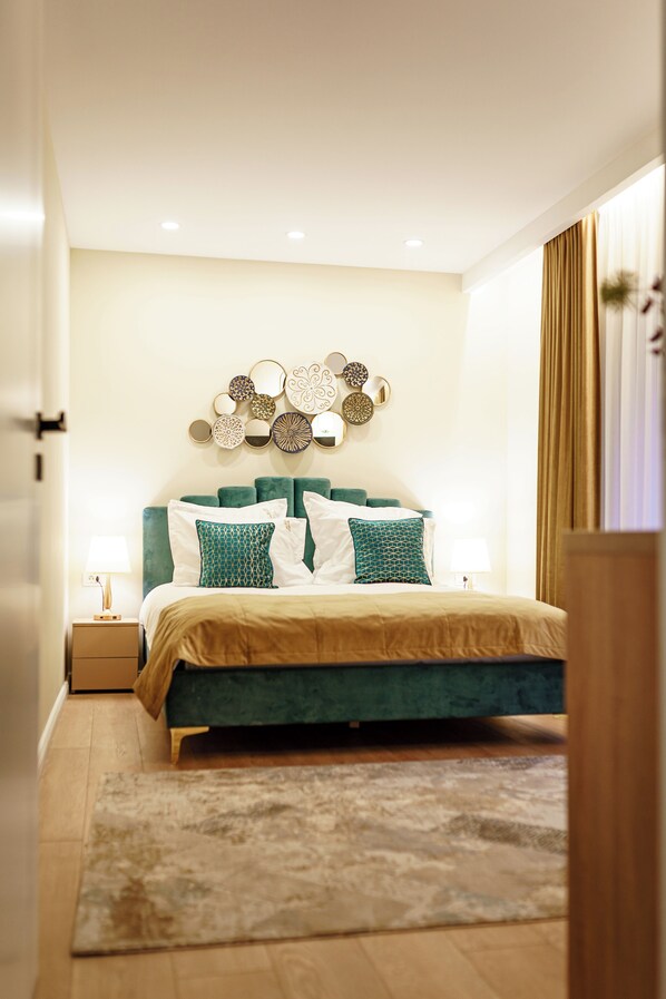 A modern bedroom with a teal bed, beige bedding, and decorative wall art. - Prestige ApartHotel Brasov (Brasov)