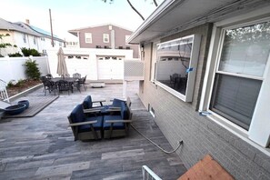 Eine Terrasse mit Gartenmöbeln, ein überdachter Sitzbereich und eine Garagentür.