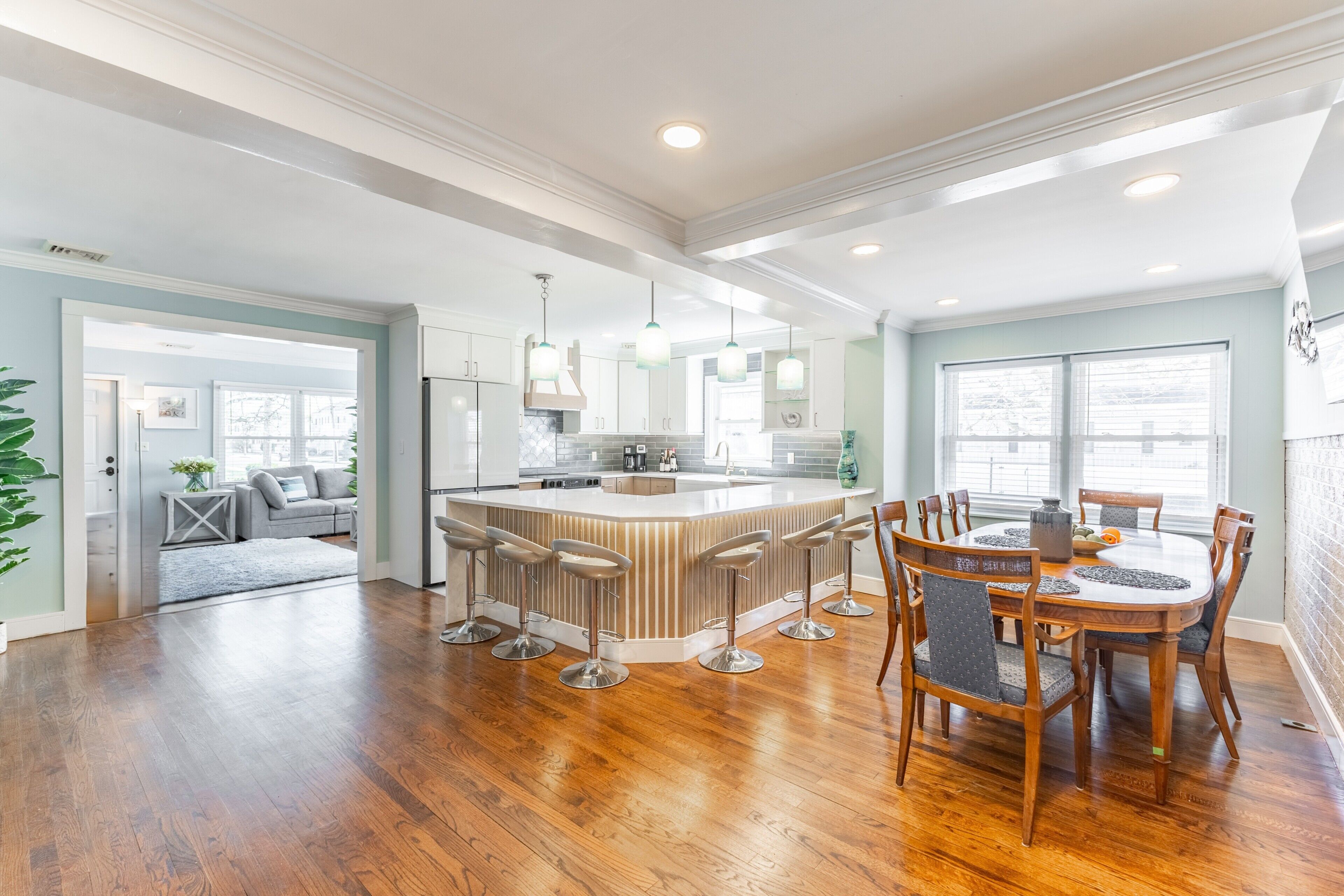 A spacious kitchen with a central island, bar stools, and a dining table with chairs.