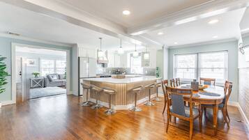 A spacious kitchen with a central island, bar stools, and a dining table with chairs.