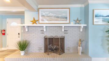 A fireplace with a brick surround, a framed picture above it, and decorative starfish.
