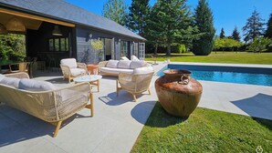 A modern outdoor living area with wicker furniture, a large planter, and a swimming pool.