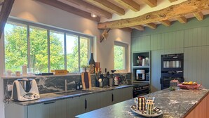 A modern kitchen with a marble countertop, wooden cabinets, and a large window providing natural light.