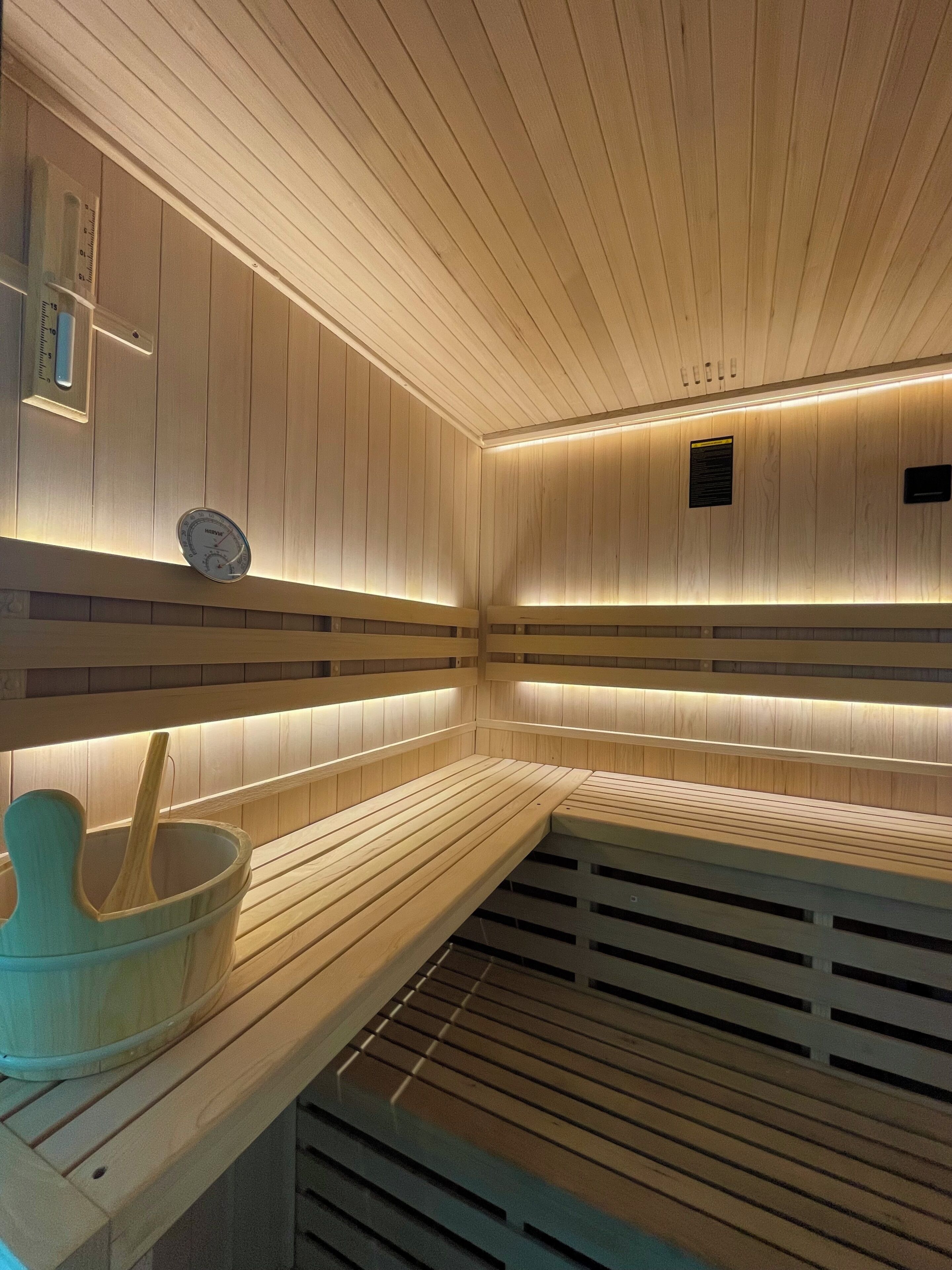 Una sauna con bancos de madera y un cubo de madera.