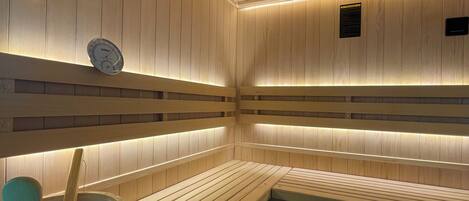 Una sauna con bancos de madera y un cubo de madera.