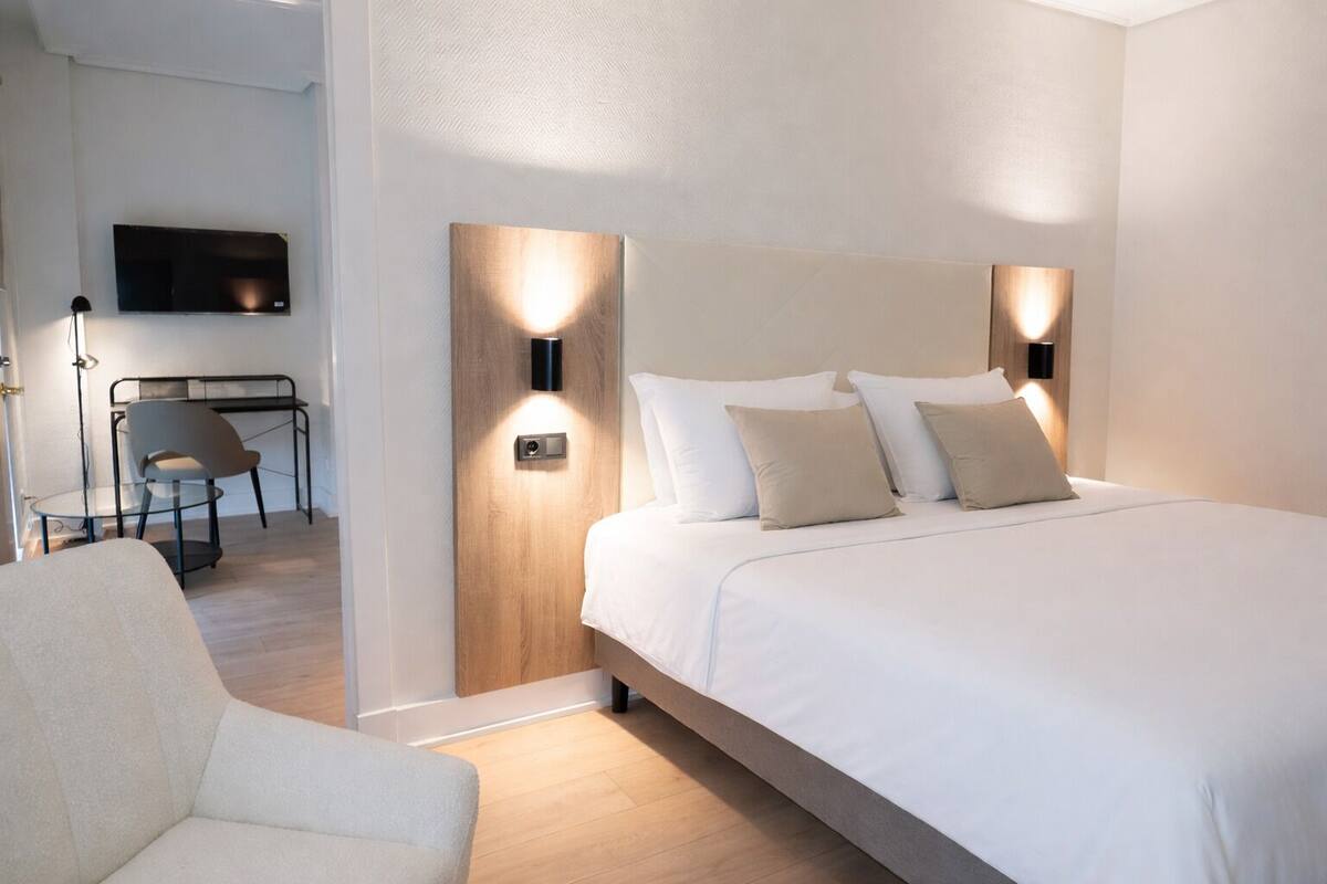 A modern hotel room with a large bed, a desk, and a chair.
