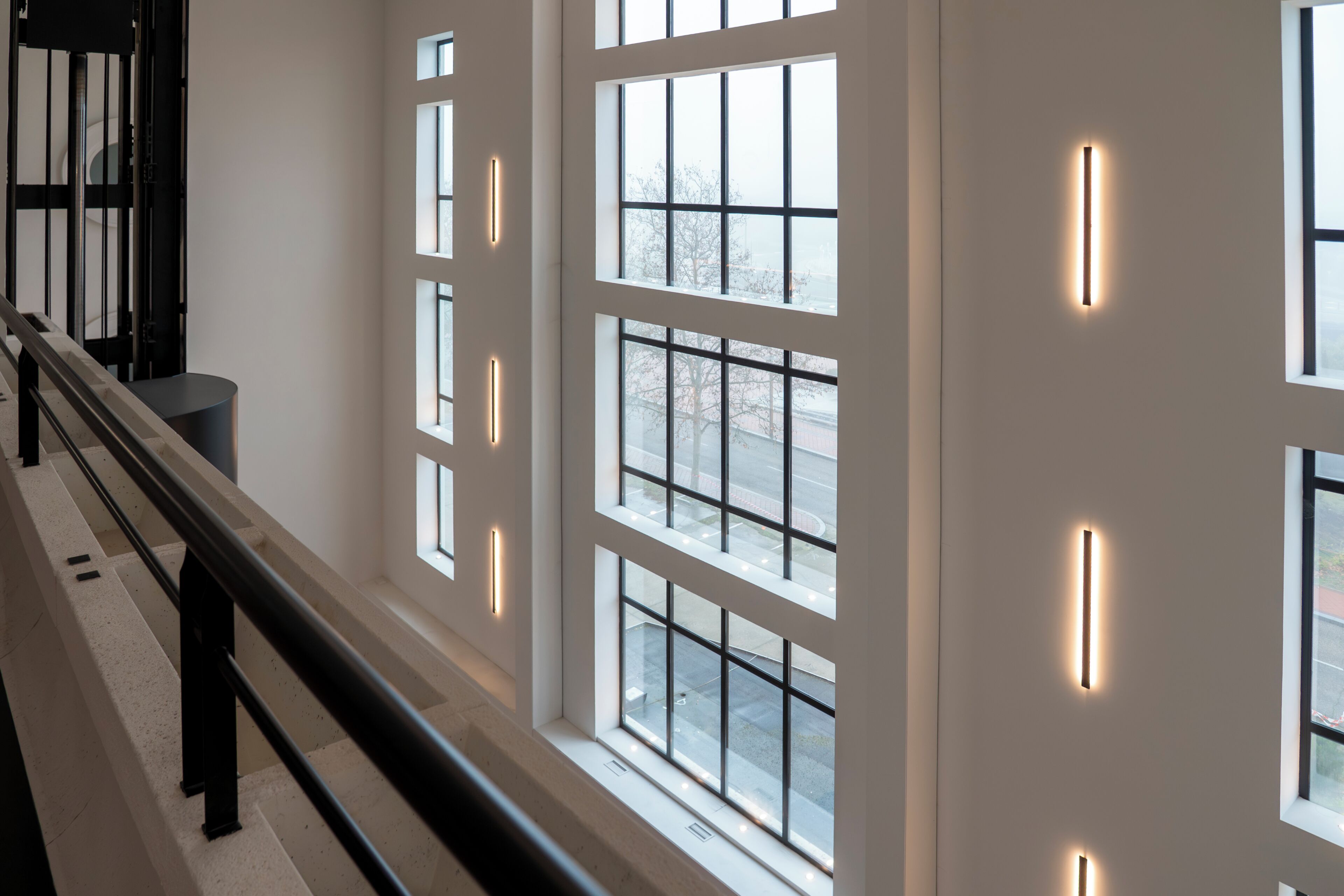 A modern interior with large windows and a staircase.