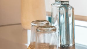 Una mesa de vidrio con dos botellas y dos vasos.