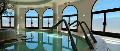An indoor swimming pool with clear views through large arched windows.