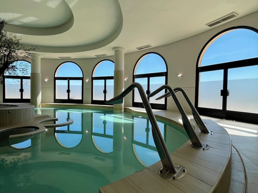 An indoor swimming pool with clear views through large arched windows.