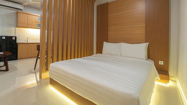 A modern hotel room with a large bed, wooden headboard, and a separate kitchenette area. - Casa Residence Bali (Kerobokan Kaja)