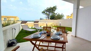 A dining area with a table set for four, outdoor chairs, and a view of the surrounding neighborhood.