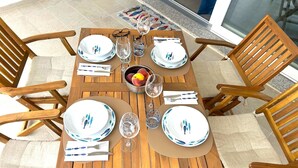 A wooden dining table set for four with matching plates, glasses, and cutlery.
