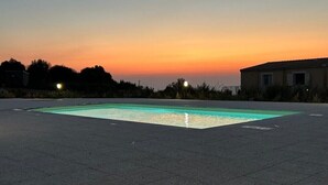 A rectangular swimming pool with a tiled deck, surrounded by a low wall.