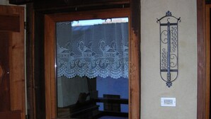 Ein Zimmer mit einem raumhohen Fenster mit Holzrahmen, einem Spitzendecke und einer Wandleuchte.