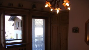 Ein Schlafzimmer mit einem hölzernen Bett, einem Fenster mit Spitzengardinen, einem Holzschrank und einer Kristallleuchter.